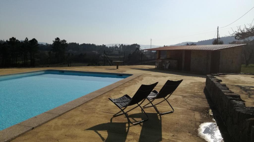 two chairs sitting next to a swimming pool at Casa na Quinta de Valinhas in Vitorino dos Piães