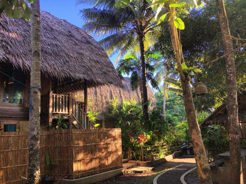 una casa con techo de paja y palmeras en Villa Monyet Java en Batukaras