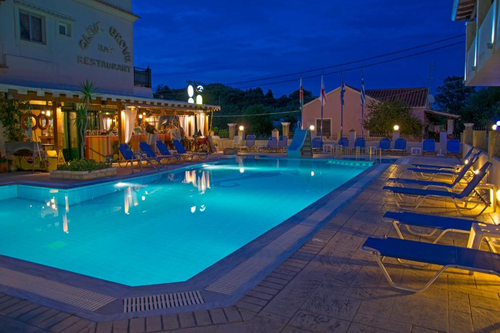 a pool at night with chairs and a bar at olivegrove in Sidari