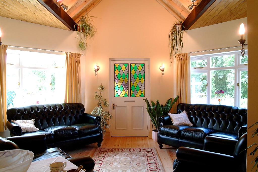 a living room with black leather couches and a stained glass window at Rosedene Guest House in Pembroke