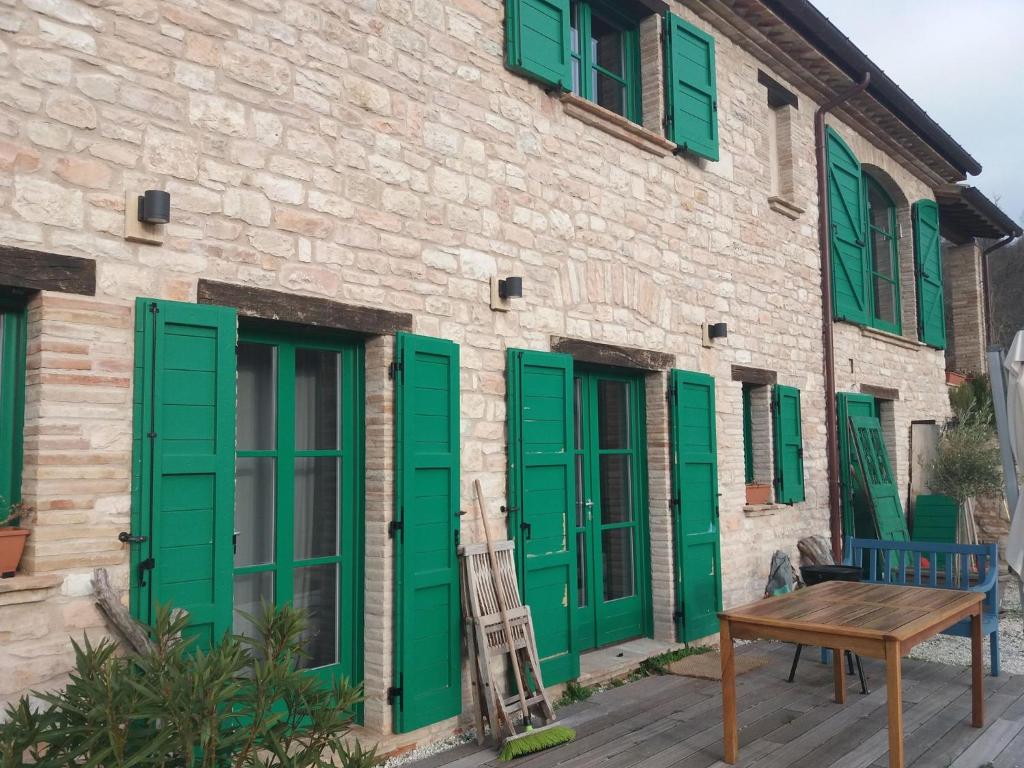 un edificio con persianas verdes y mesa de madera en Ca'Ceccarone, en Cagli