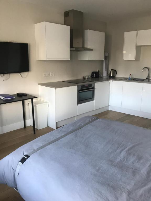 uma cozinha com armários brancos e uma cama grande em The Annex em Ickenham