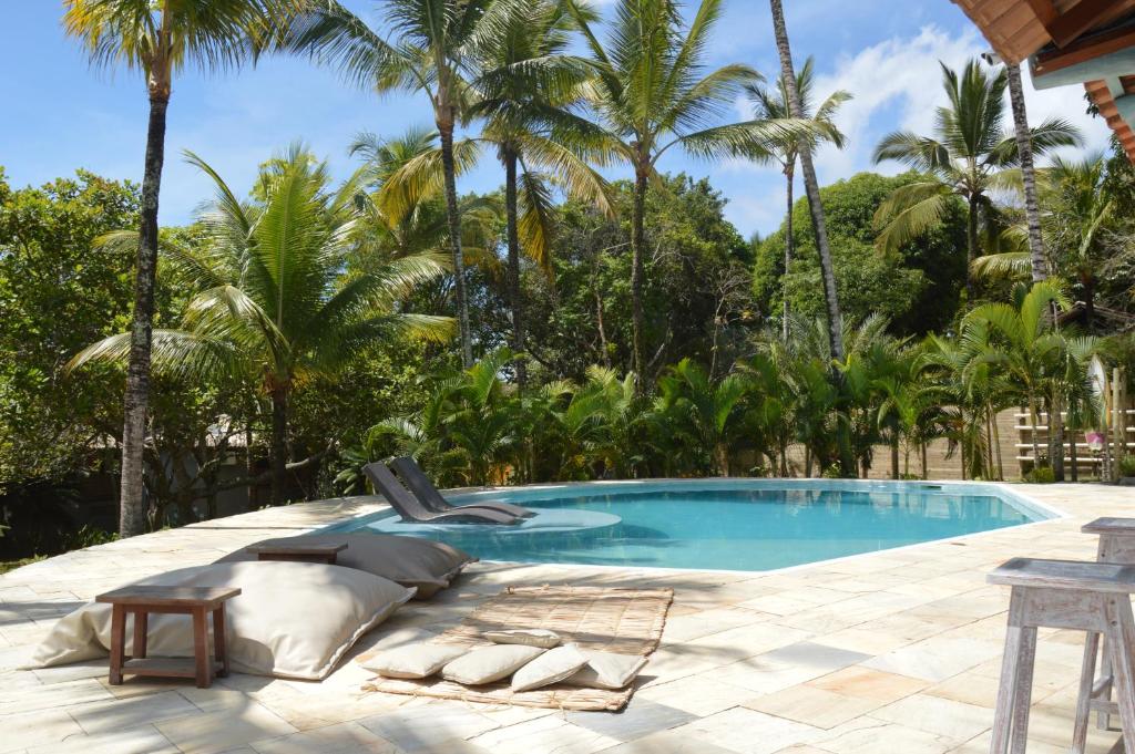 a swimming pool with a chaise lounge and palm trees at Pousada Jacarandá by Rivaj in Trancoso
