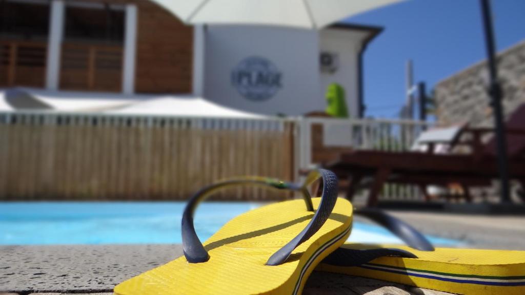 a pair of yellow flip flops sitting next to a swimming pool at Cote Plage in La Saline les Bains