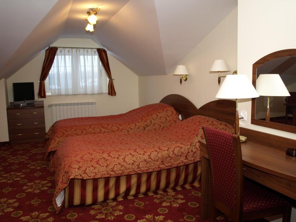 a bedroom with a bed and a desk and a mirror at Hotel Relaks in Wola Ducka