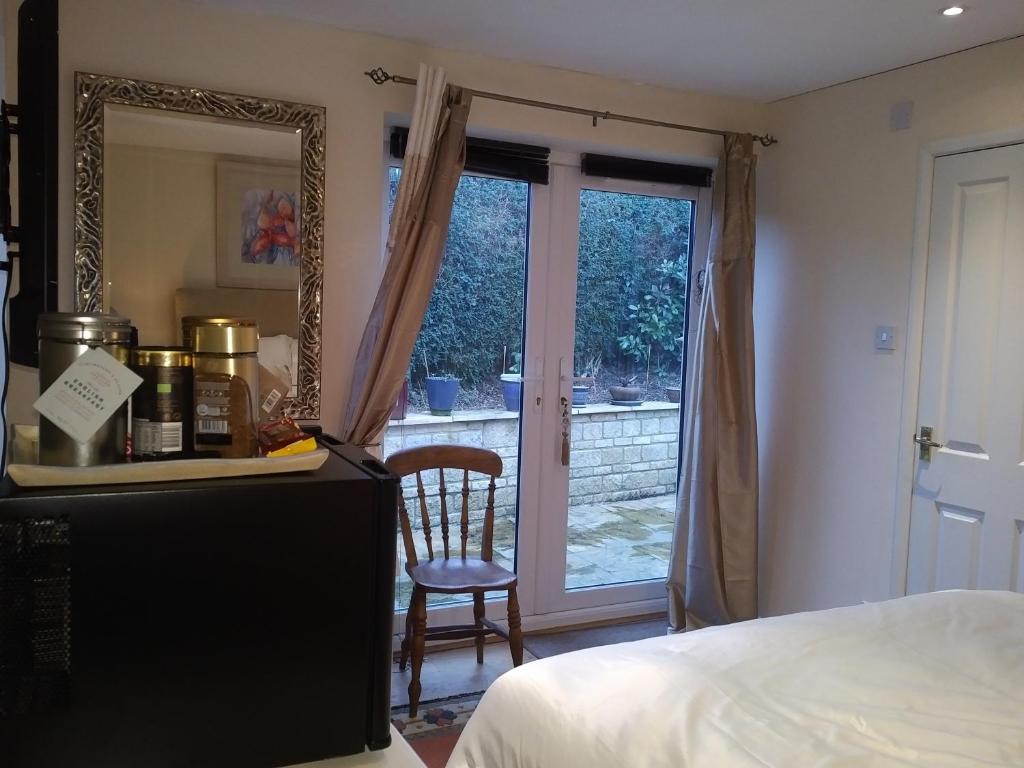 1 dormitorio con cama, espejo y silla en Sunny Patch, en Stroud