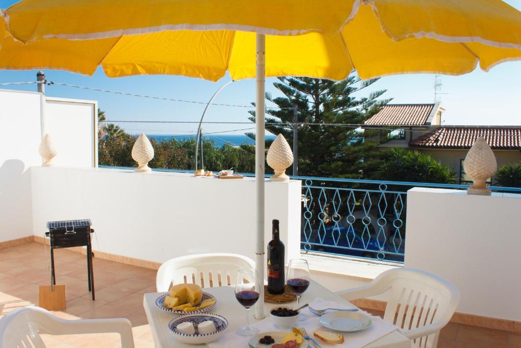 - une table avec un parapluie jaune et une bouteille de vin dans l'établissement Casa Le Pigne, à Avola