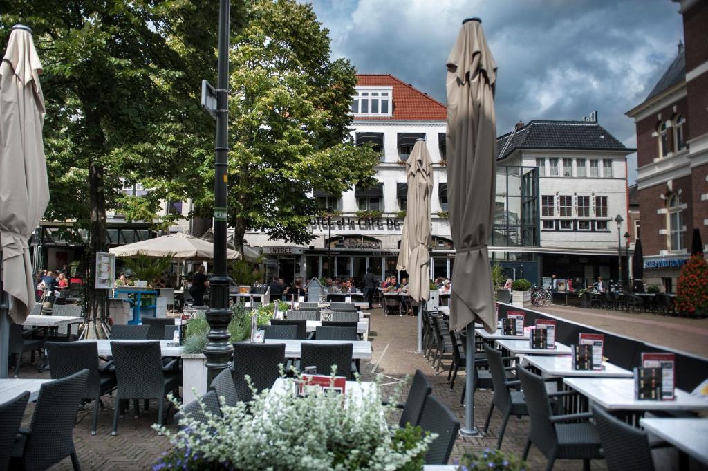 an outdoor restaurant with tables and umbrellas at Hotel et le Cafe de Paris in Apeldoorn