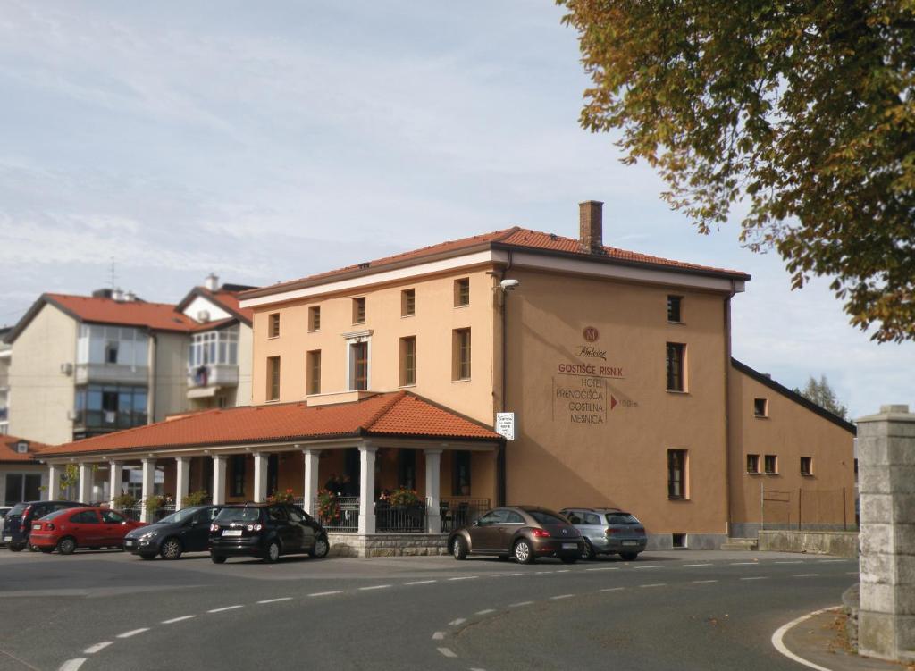 a building with cars parked on the side of a street at Guesthouse Risnik in Divača