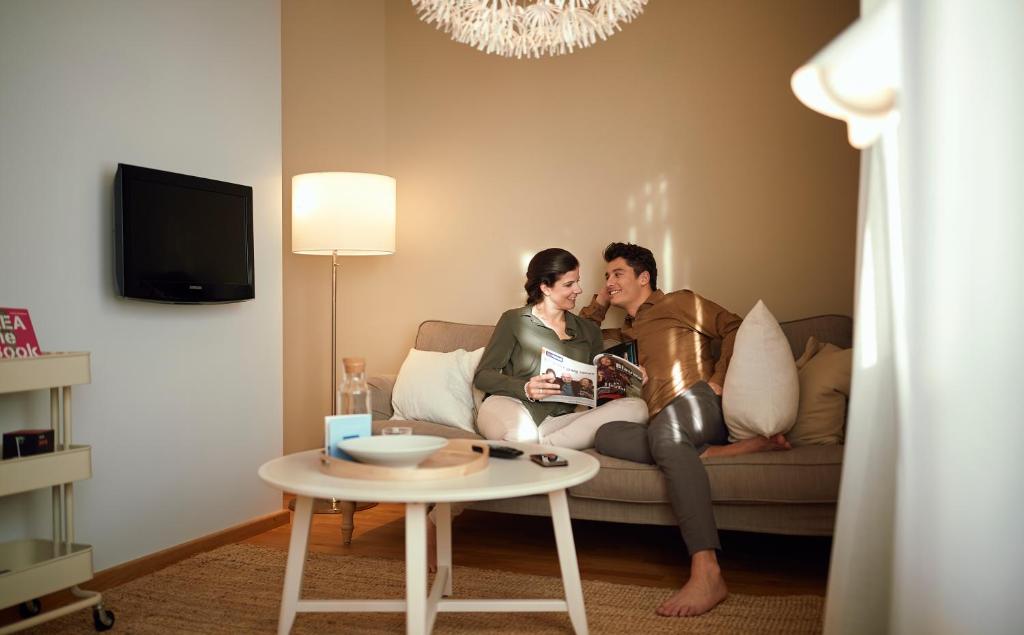 a man and woman sitting on a couch in a living room at WestCord Hotel Delft in Delft