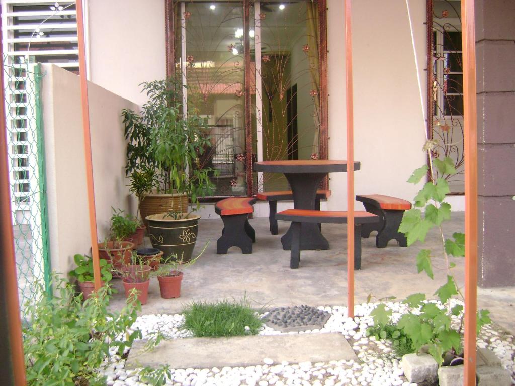 a patio with plants and a table and benches at Homestay Amsyarah in Seri Iskandar