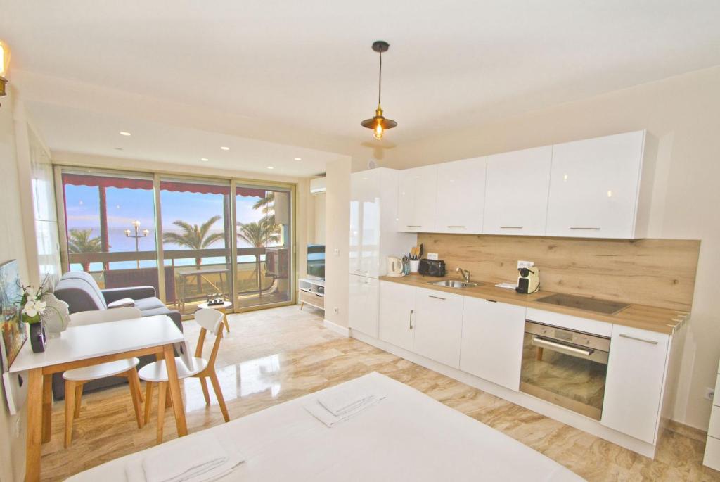 尼斯的住宿－PROMENADE HOLIDAY - COSY SEA FRONT STUDIO，厨房配有白色橱柜、桌子和用餐室。
