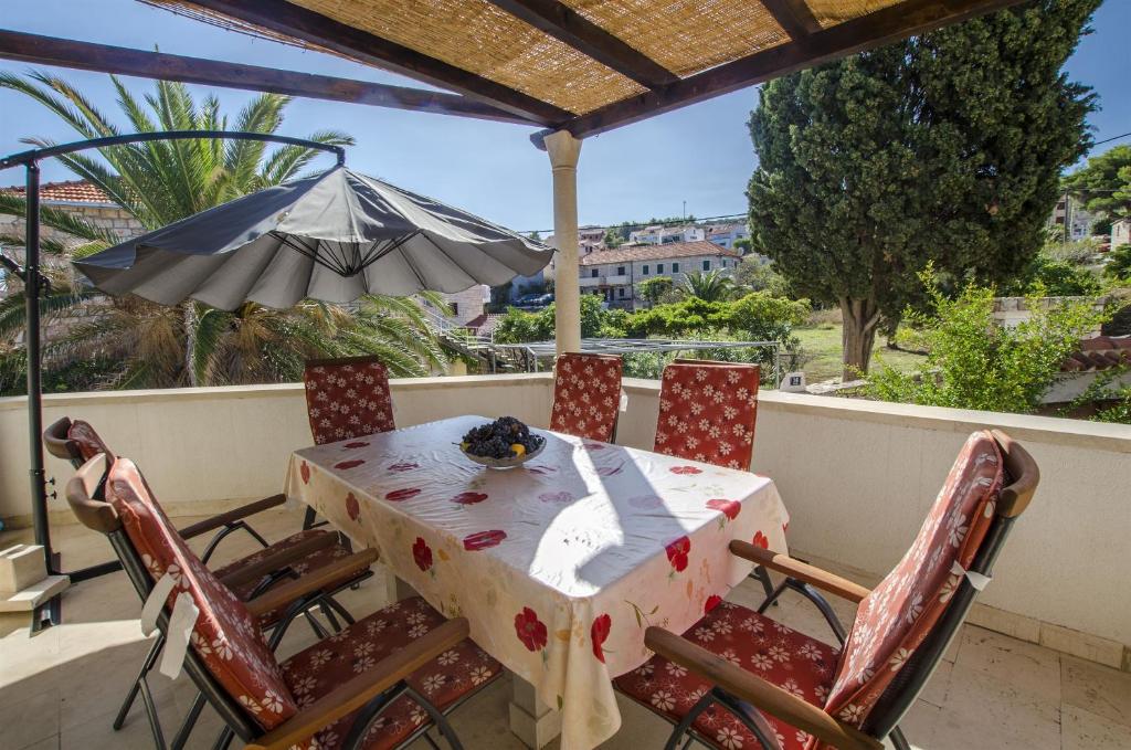 a table and chairs on a balcony with an umbrella at Apartments Mare in Postira