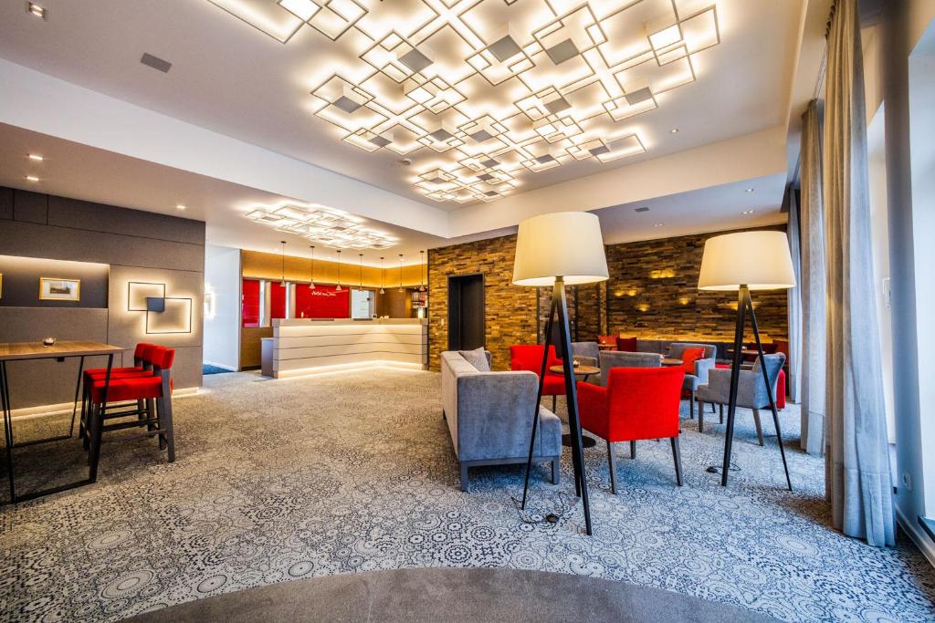富爾達的住宿－德姆酒店，酒店大堂设有红色椅子和桌子