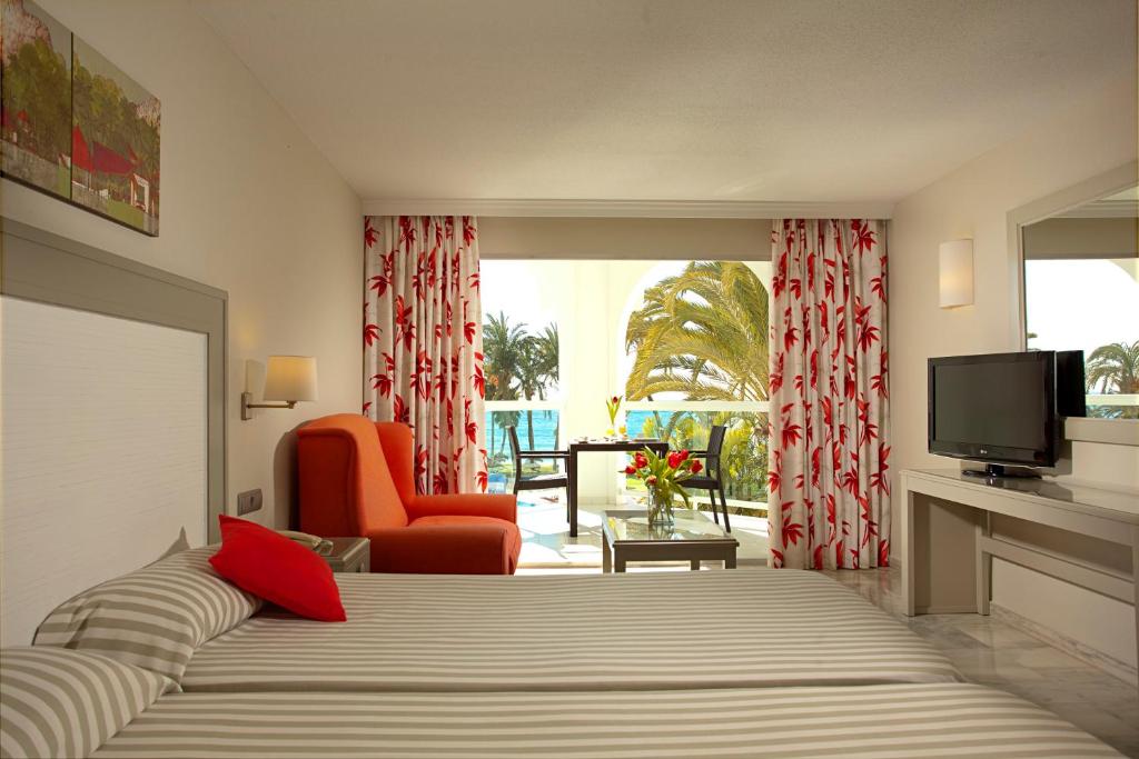a bedroom with a bed and a television and a chair at Ona Marinas de Nerja Spa Resort in Nerja