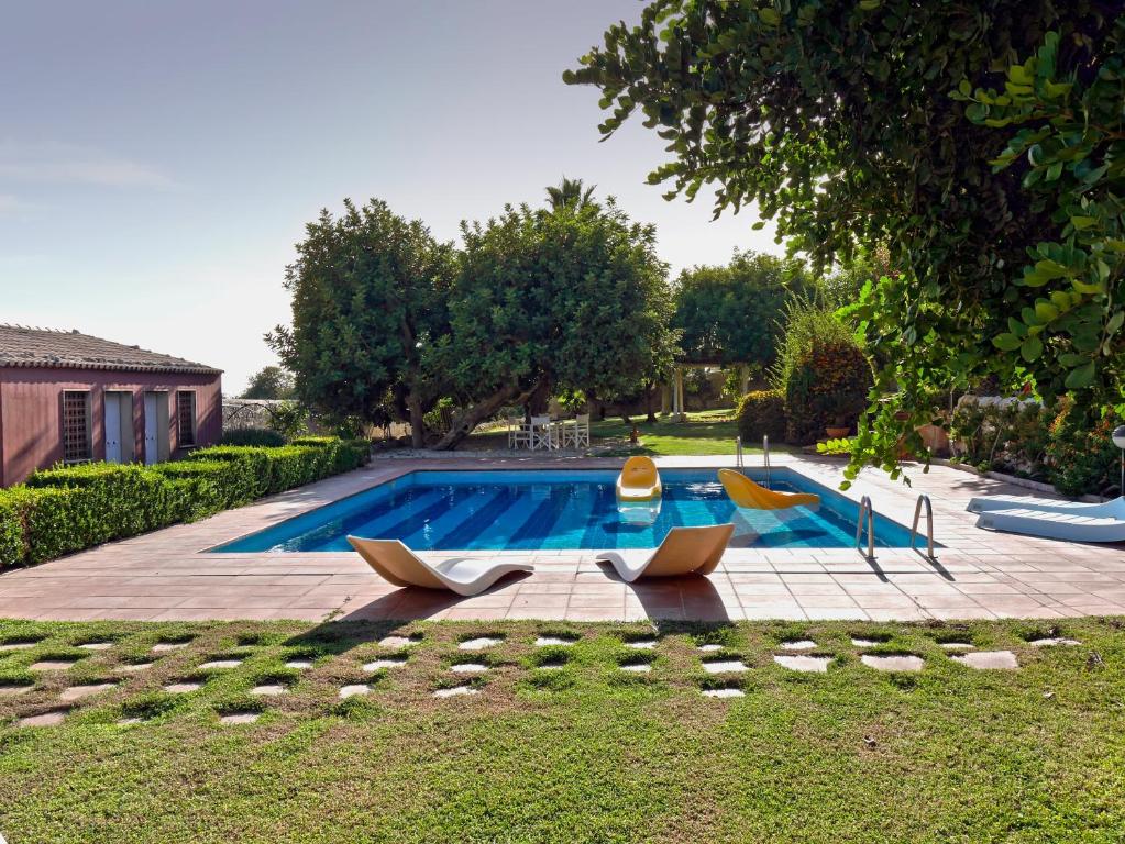 a swimming pool with chairs in a yard at La Casetta Sicilian Cottage in Case Rosolia