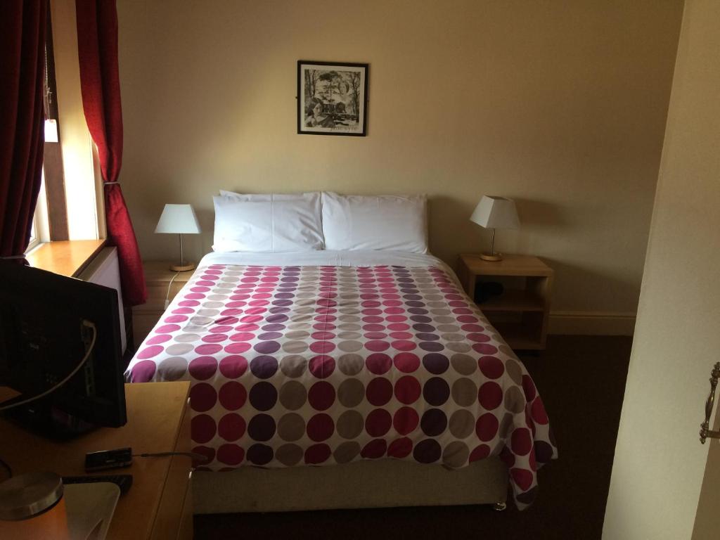 1 dormitorio con 1 cama con colcha colorida en The Apothecary Guest House, en Haworth