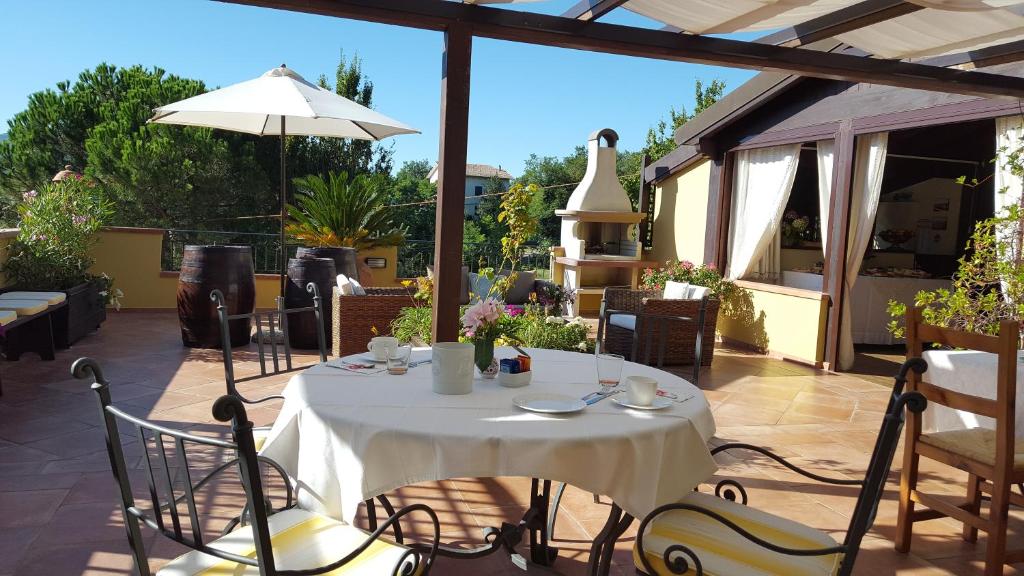 een patio met een tafel en stoelen en een parasol bij B&B La Valle in Novafeltria