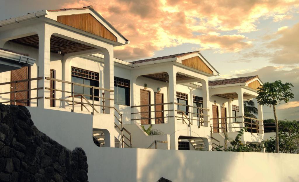 a house with a sunset in the background at Arena Blanca Eco Hotel in Puerto Baquerizo Moreno