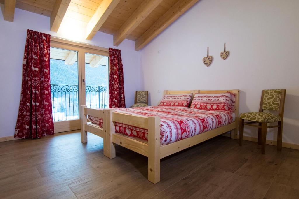 um quarto com uma cama e uma grande janela em Olimpic Hostel em Schilpario