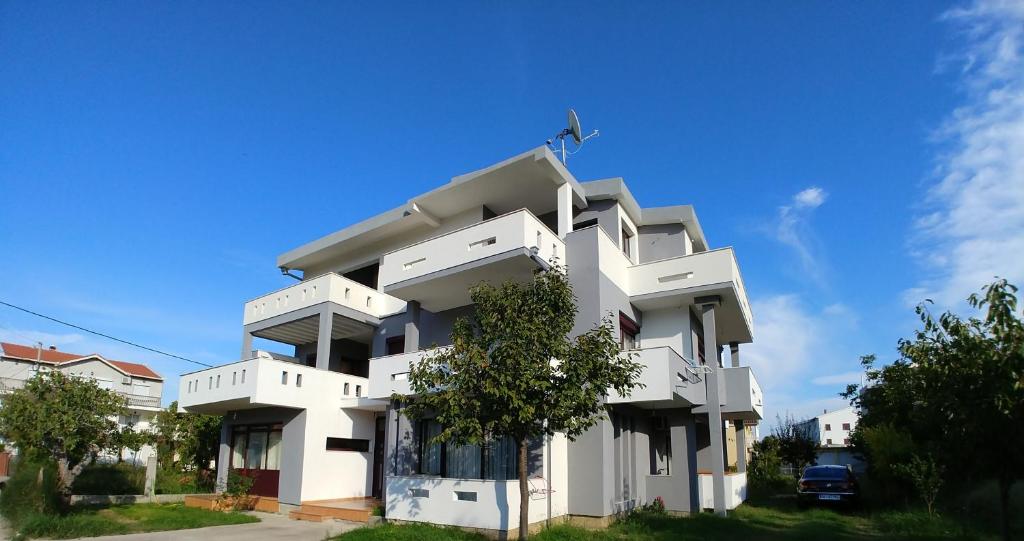 un edificio blanco con un árbol delante en Studios M, en Ulcinj