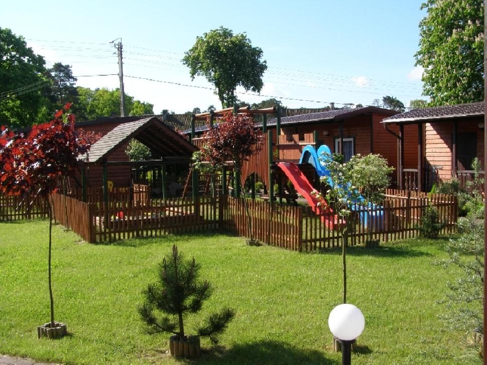 un patio con una valla y un parque infantil en Domki Przy Lesie, en Stegna