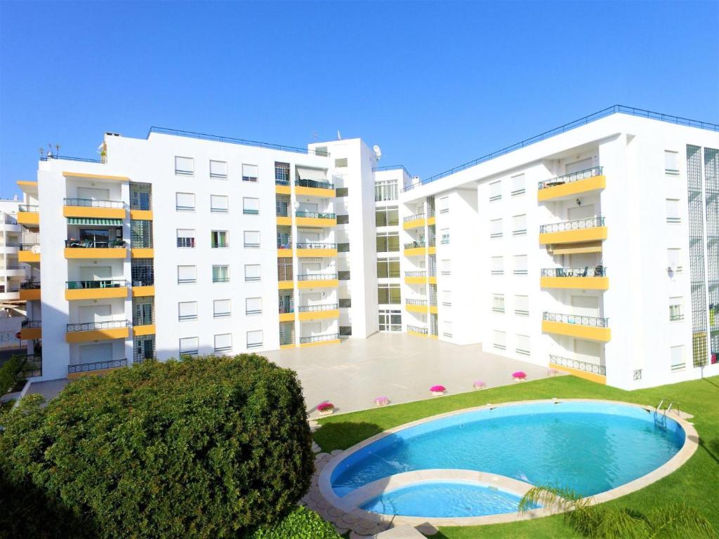 an apartment complex with a swimming pool in front of two buildings at Quiet apartment overlooking the swimming pool in Armação de Pêra