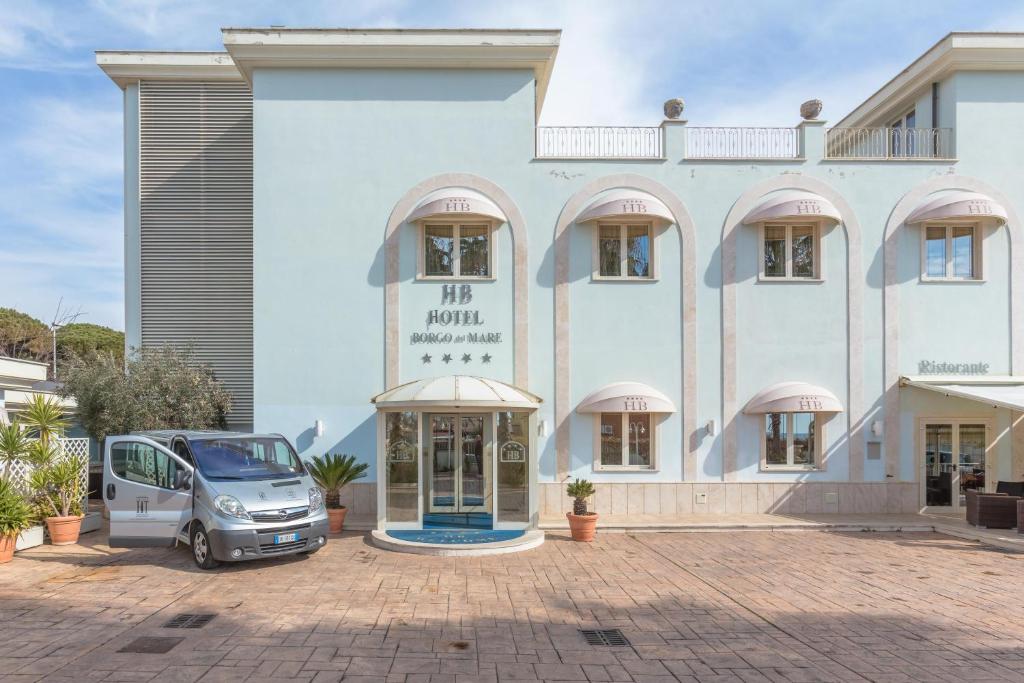 a car parked in front of a large building at Hotel Borgo Del Mare in Civitavecchia