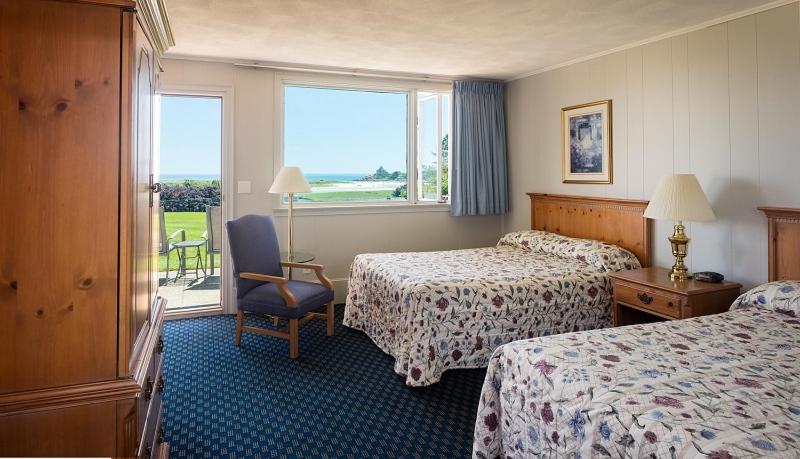 a hotel room with two beds and a chair and a window at The Vista in Gloucester