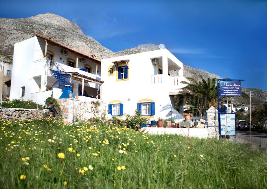 a white house with a field of flowers at Themelina Studios in Emborios Kalymnos
