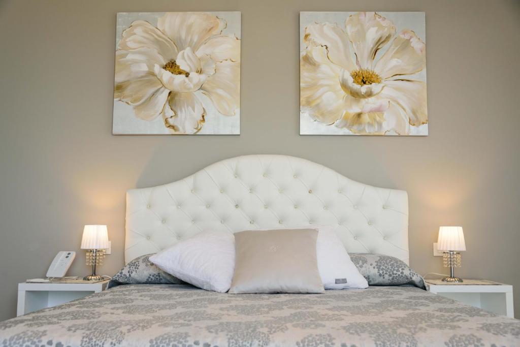 a bedroom with a white bed with three pictures on the wall at Bellariva Monopoli B&B e Relax in Monopoli