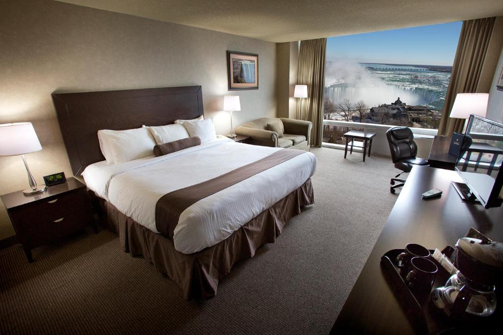 a hotel room with a bed and a large window at The Oakes Hotel Overlooking the Falls in Niagara Falls