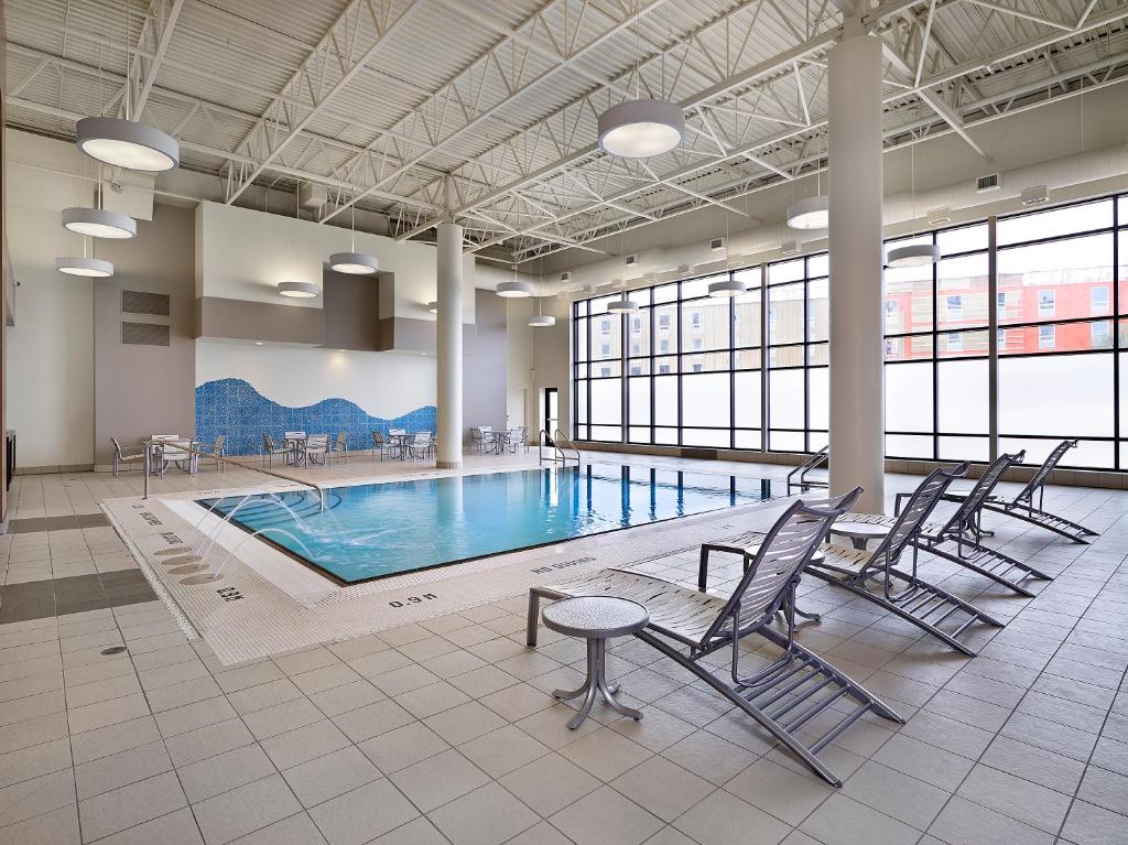 een zwembad met stoelen en een tafel in een gebouw bij DoubleTree by Hilton West Edmonton in Edmonton
