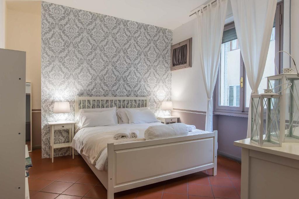 フィレンツェにあるDowntown suite Florenceの白いベッドと壁が備わるベッドルーム1室が備わります。