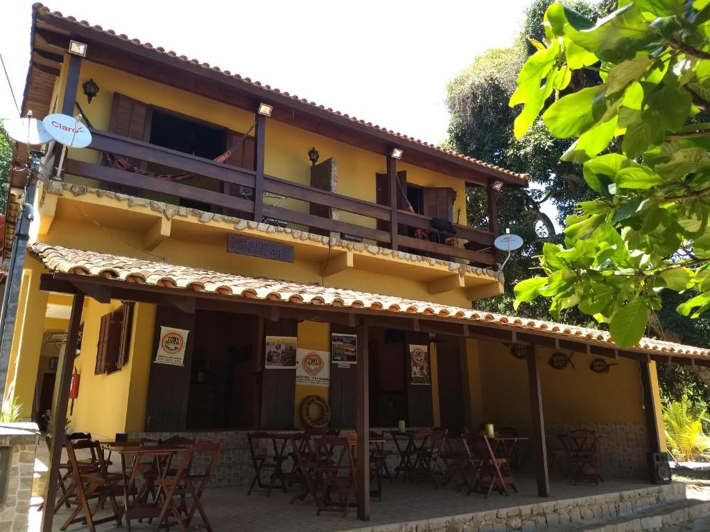 een gebouw met tafels en stoelen ervoor bij Pousada Tony Montana in Praia de Araçatiba
