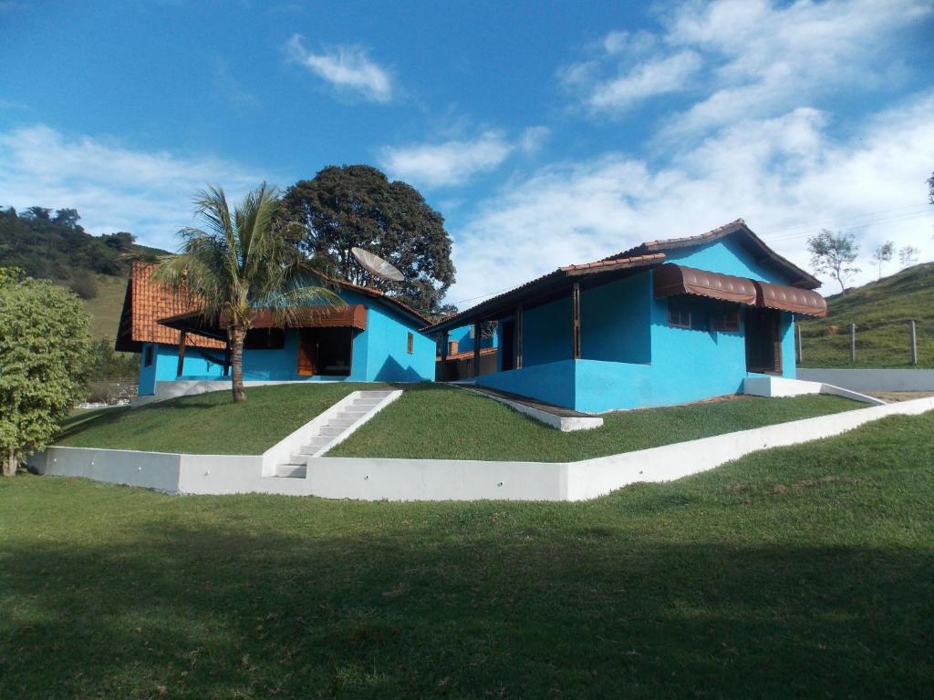 a blue house with a palm tree in front of it at Pousada Som das Águas Bueno Brandão in Bueno Brandão