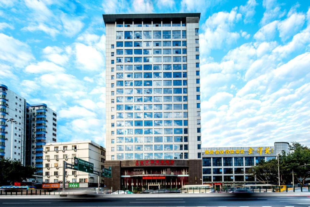 a tall building in a city with clouds in the sky at Guangzhou Jin Wan Li Business Hotel in Guangzhou