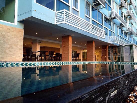 a house with a swimming pool in front of a building at Nantra Pattaya Baan Ampoe Beach in Na Jomtien