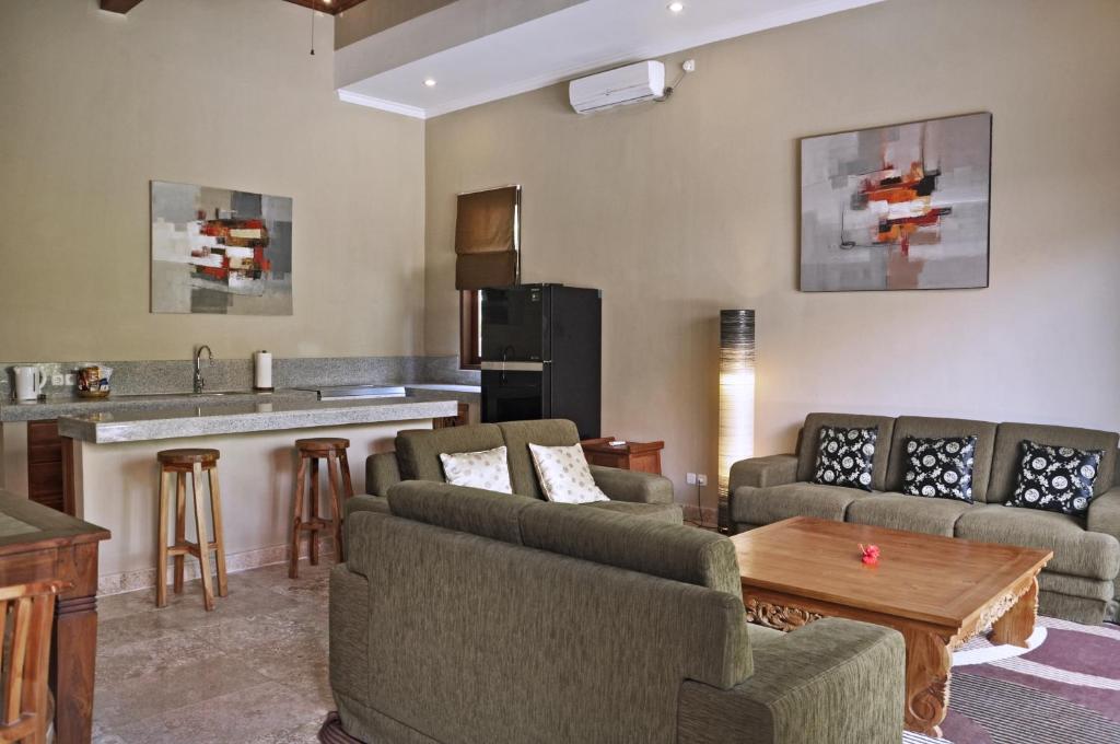 a living room with two couches and a kitchen at Bayshore Residence in Candidasa