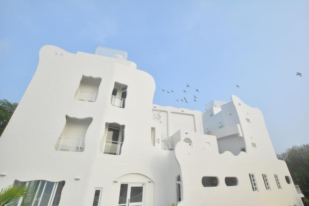 a building in santorini with birds flying around it at Mare Cielo in Xiaoliuqiu