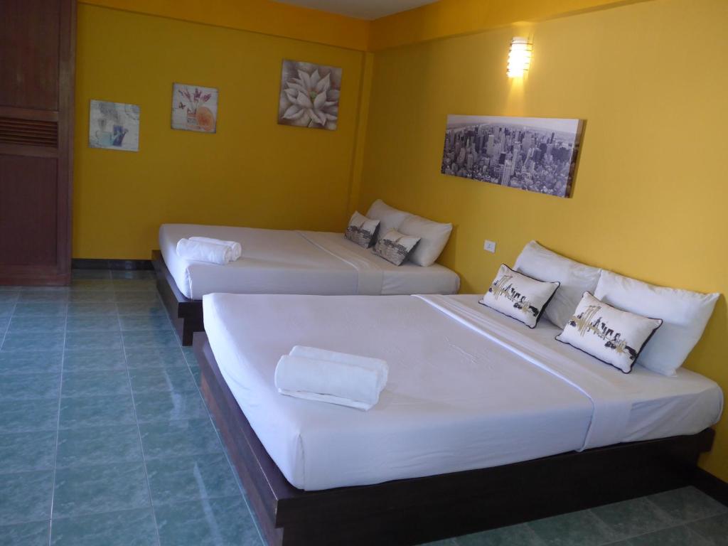 two beds in a room with yellow walls at Forum House Hotel Krabi in Krabi