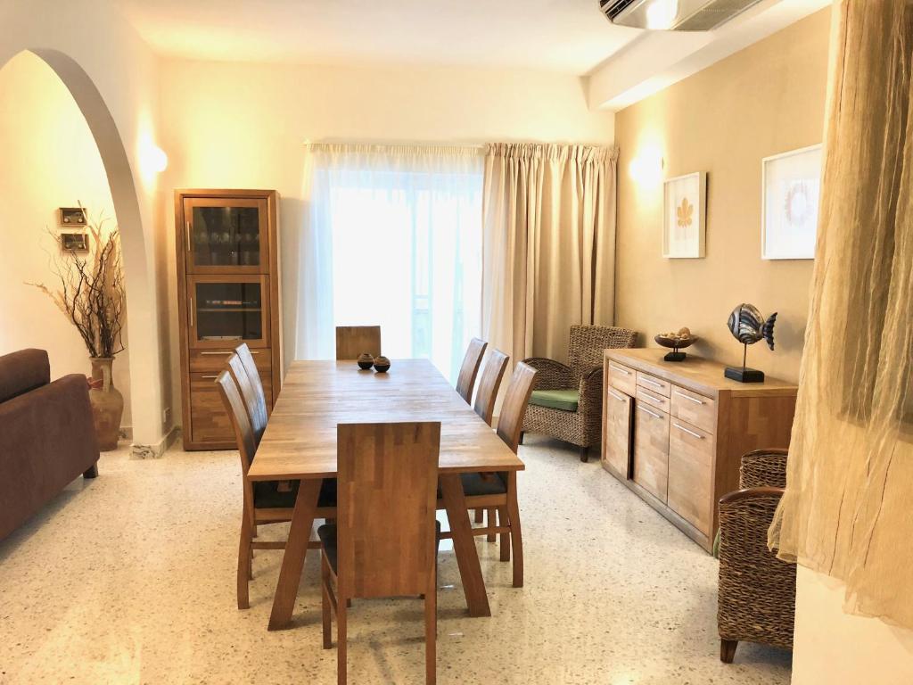 una sala da pranzo con tavolo e sedie in legno di Sands Apartments a San Pawl il-Baħar