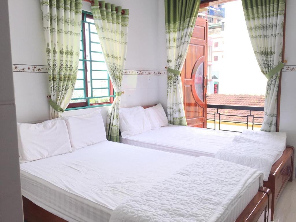 two beds in a room with a window at Nhà nghỉ Sunrise in Quy Nhon