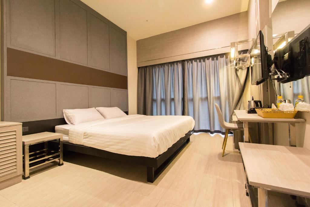 Habitación de hotel con cama, escritorio y TV. en Lazy Sunday hostel en Bangkok