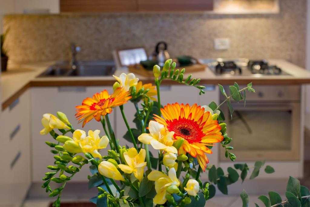 eine Vase voller gelber und oranger Blumen in der Küche in der Unterkunft Biennale Ca Dario in Venedig
