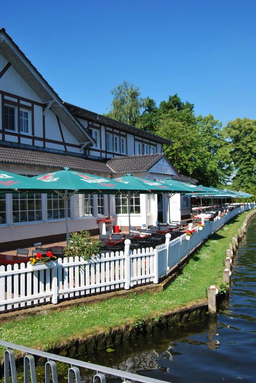 a building with tables and umbrellas next to a river at Neu-Helgoland in Berlin