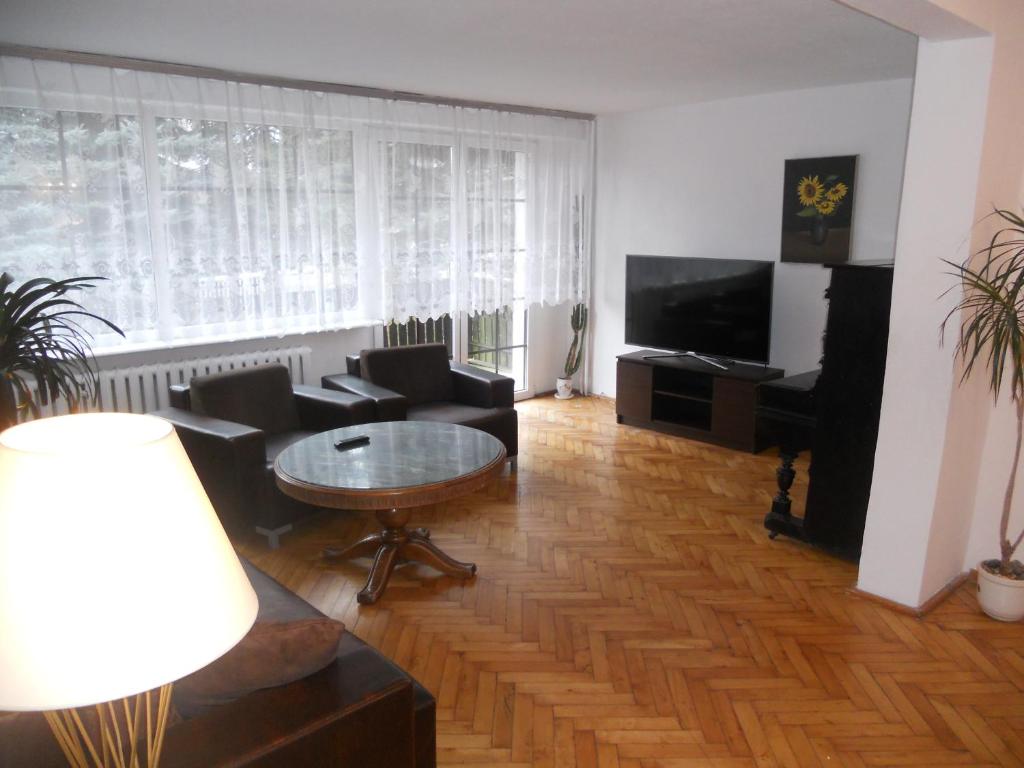 een woonkamer met een tafel en stoelen en een televisie bij Apartament Turystyczny w Stepnicy in Stepnica