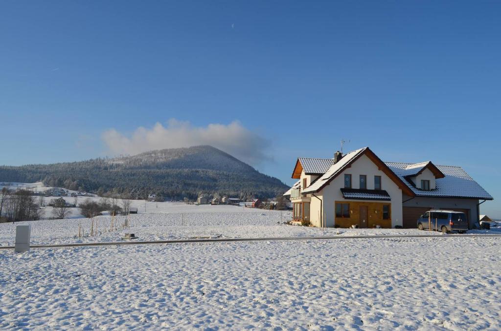 a house in the snow with a mountain in the background at Pokoje na Wzgórzu in Kasina Wielka