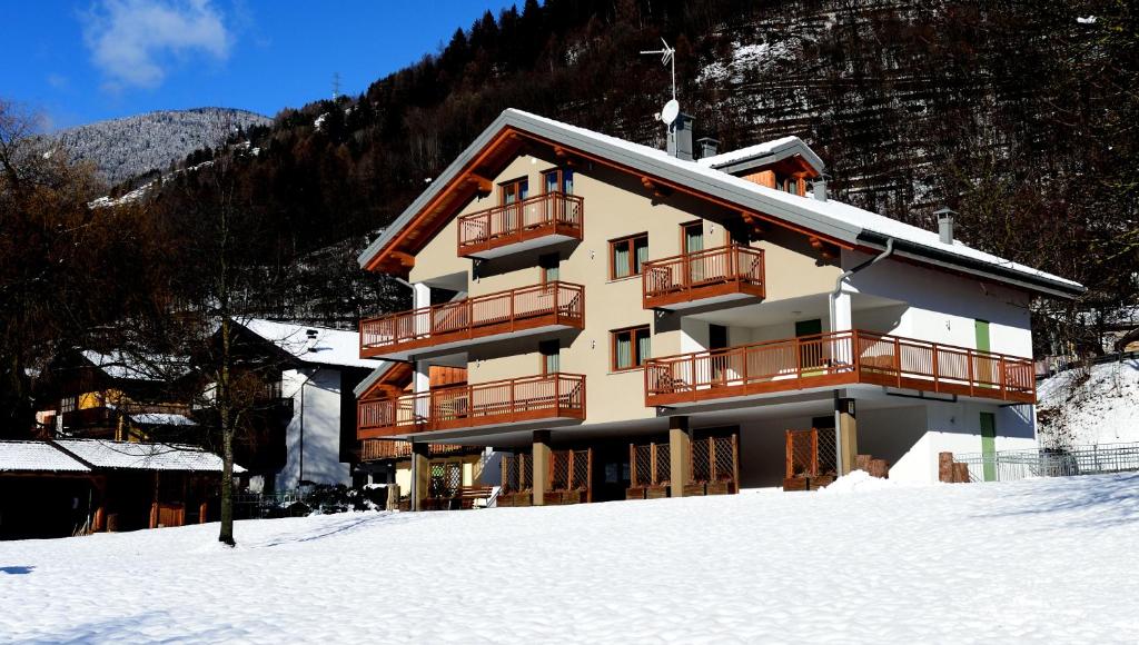 a large building in the snow in front of a mountain at La Casa al Noce in Mezzana