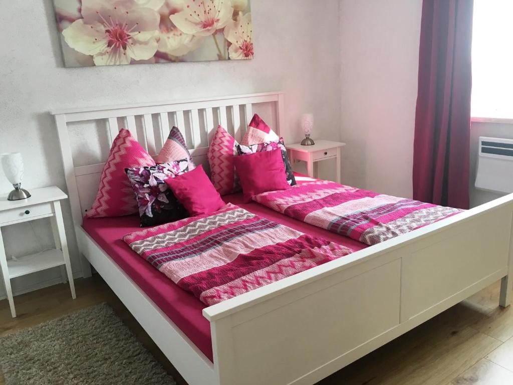 a large white bed with pink pillows on it at Alpenaquarium Grüblsee - FEWO Monika in Vordernberg